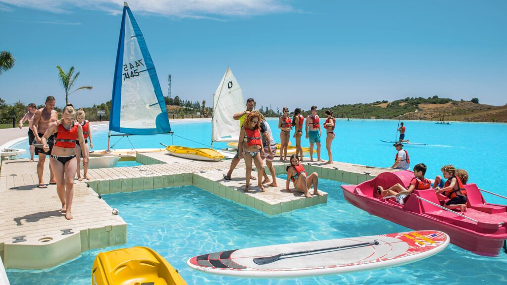 Young people on a dock with sailboats, kayaks and paddleboards at a Crystal Lagoons amenity