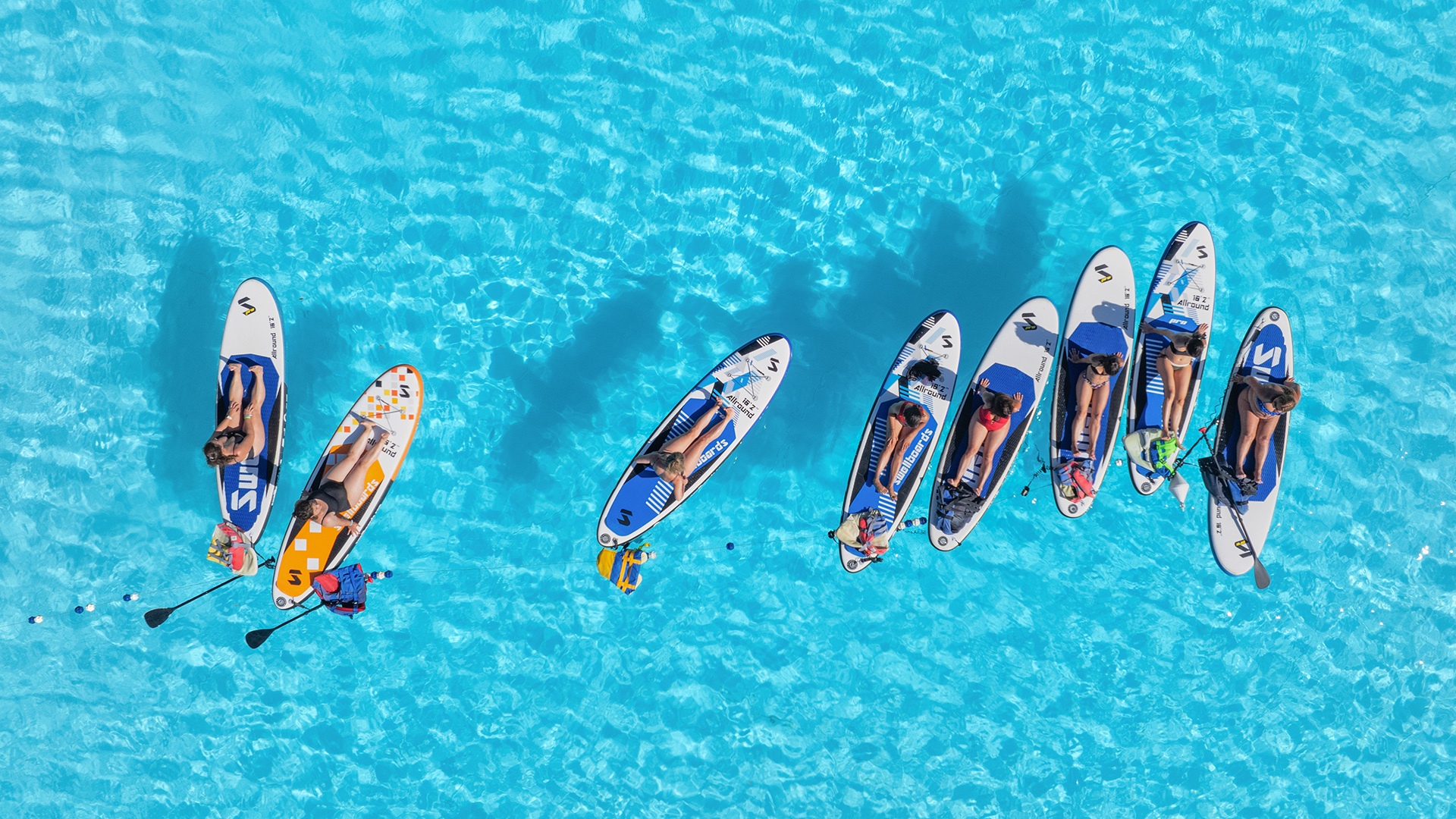 Paddleboards lined up on turquoise water for water sports and beach equipment rentals