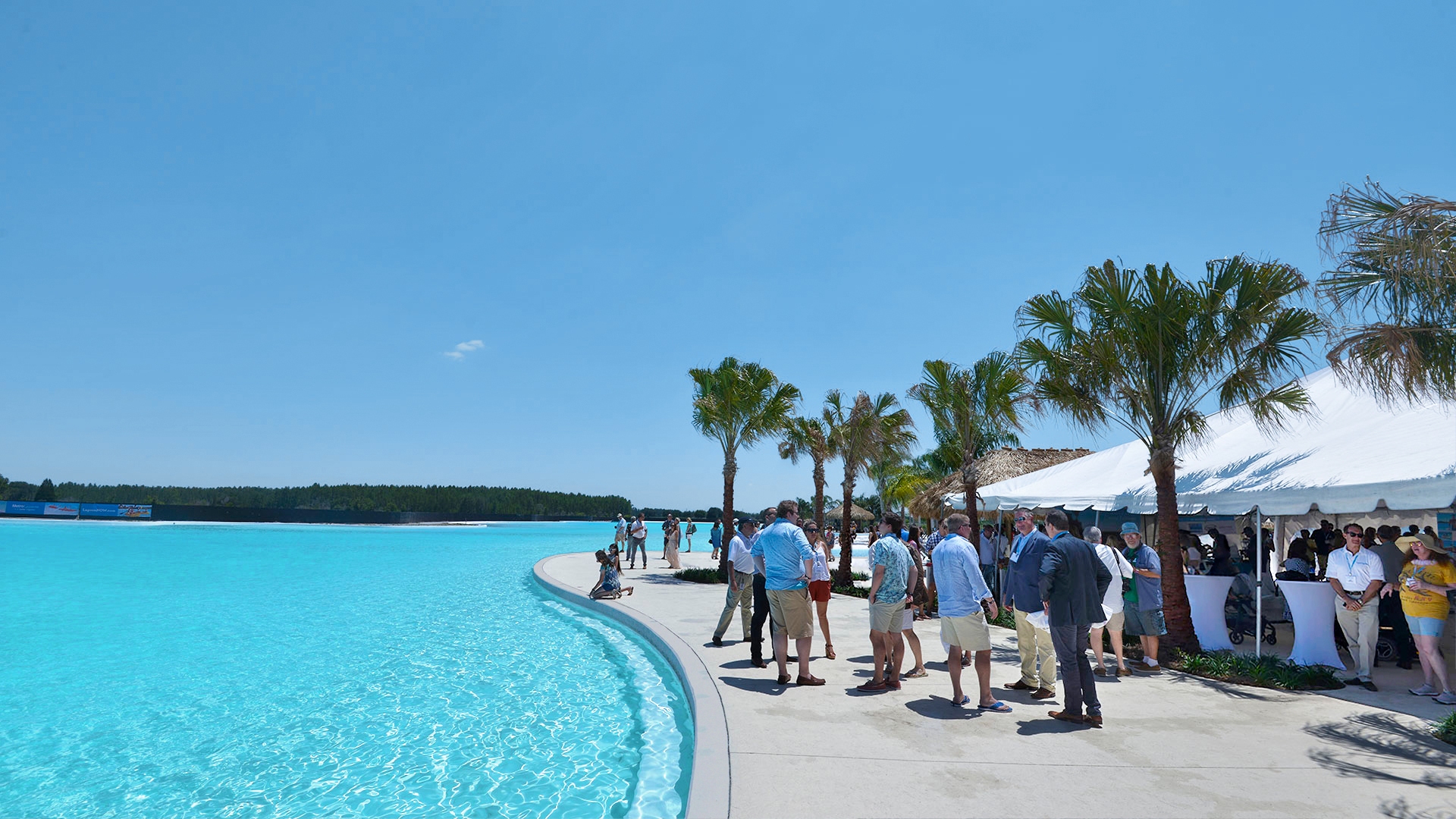 Trade fair attendees gathered along the edge of a turquoise lagoon