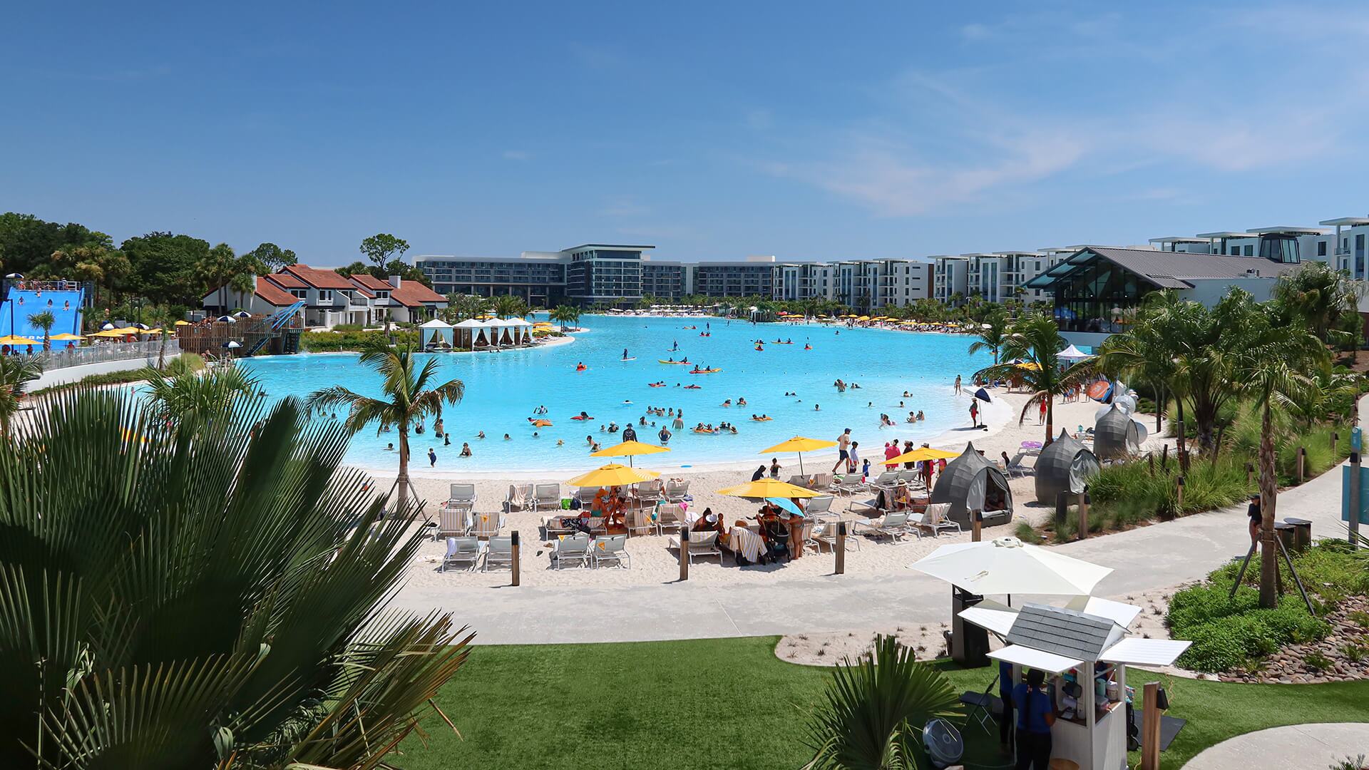 Elevated view of a Crystal Lagoons project with beach areas, amenities and surrounding buildings