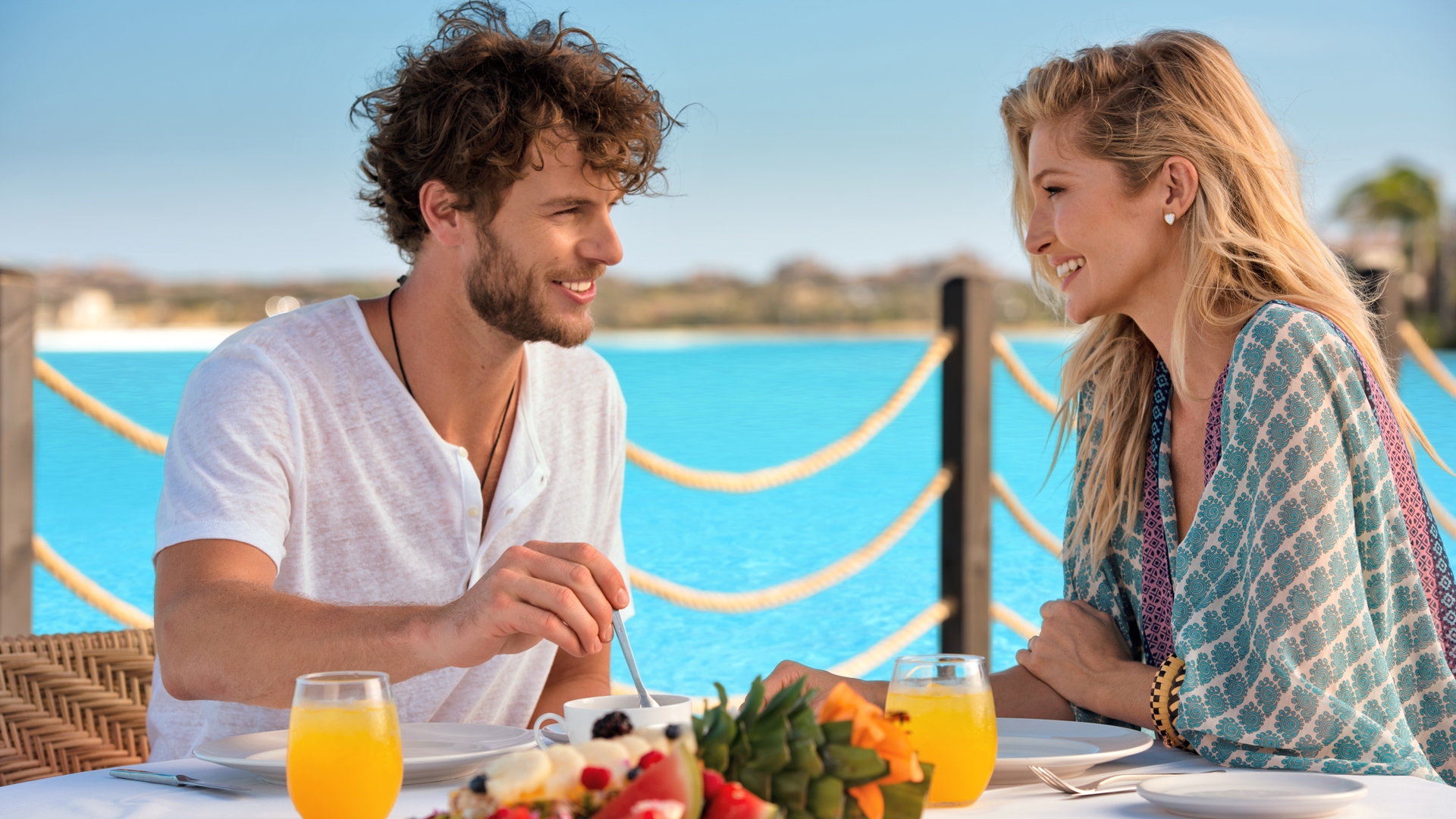 Couple enjoying breakfast on a deck overlooking the turquoise lagoon at Diamante Cabo San Lucas, Mexico