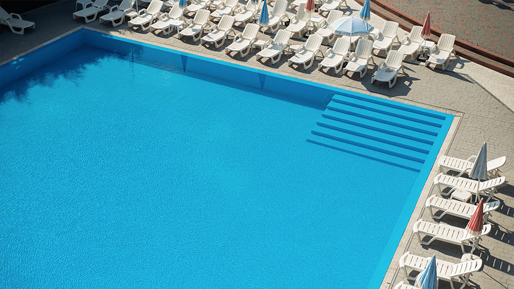 Aerial view of a traditional rectangular commercial swimming pool lined with sun loungers