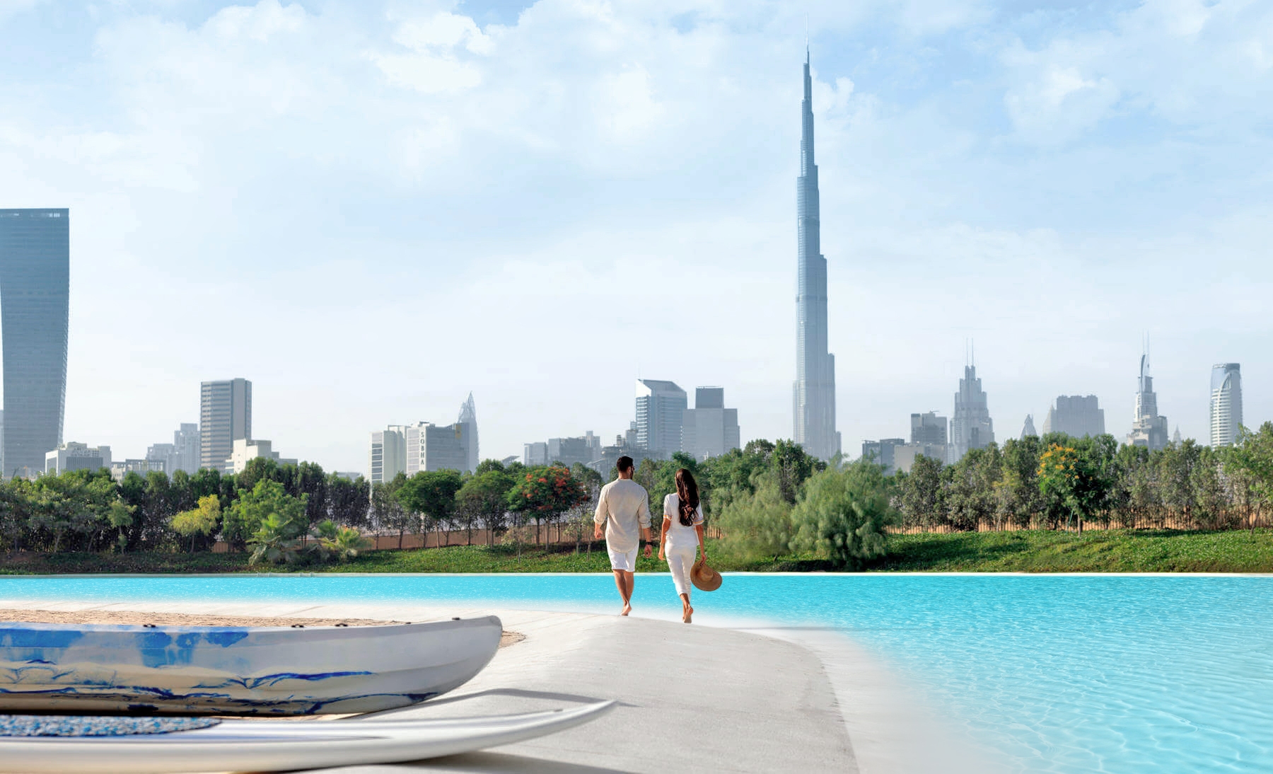 Couple walking along the MBRC District 1 lagoon shoreline with the Dubai skyline and Burj Khalifa in the background
