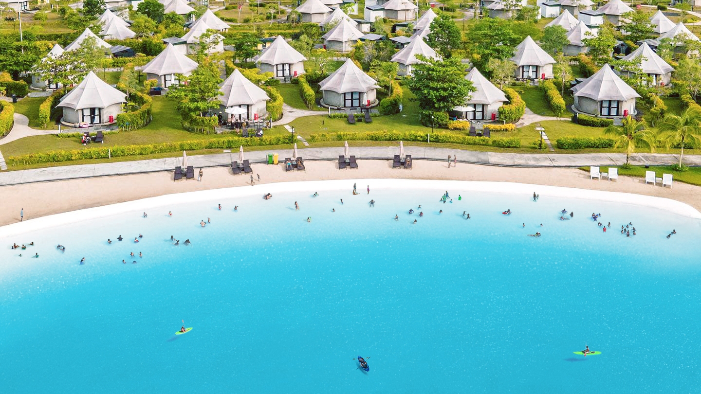Aerial view of glamping tents beside the white sand lagoon at Treasure Bay Bintan resort in Indonesia