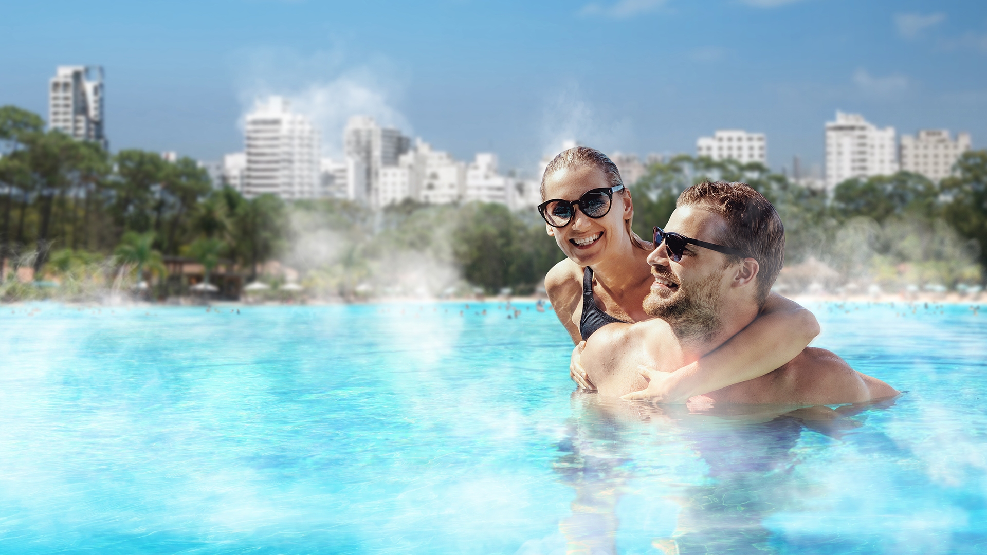 Pareja relajándose en una laguna eco-calefaccionada de Crystal Lagoons con agua turquesa tibia