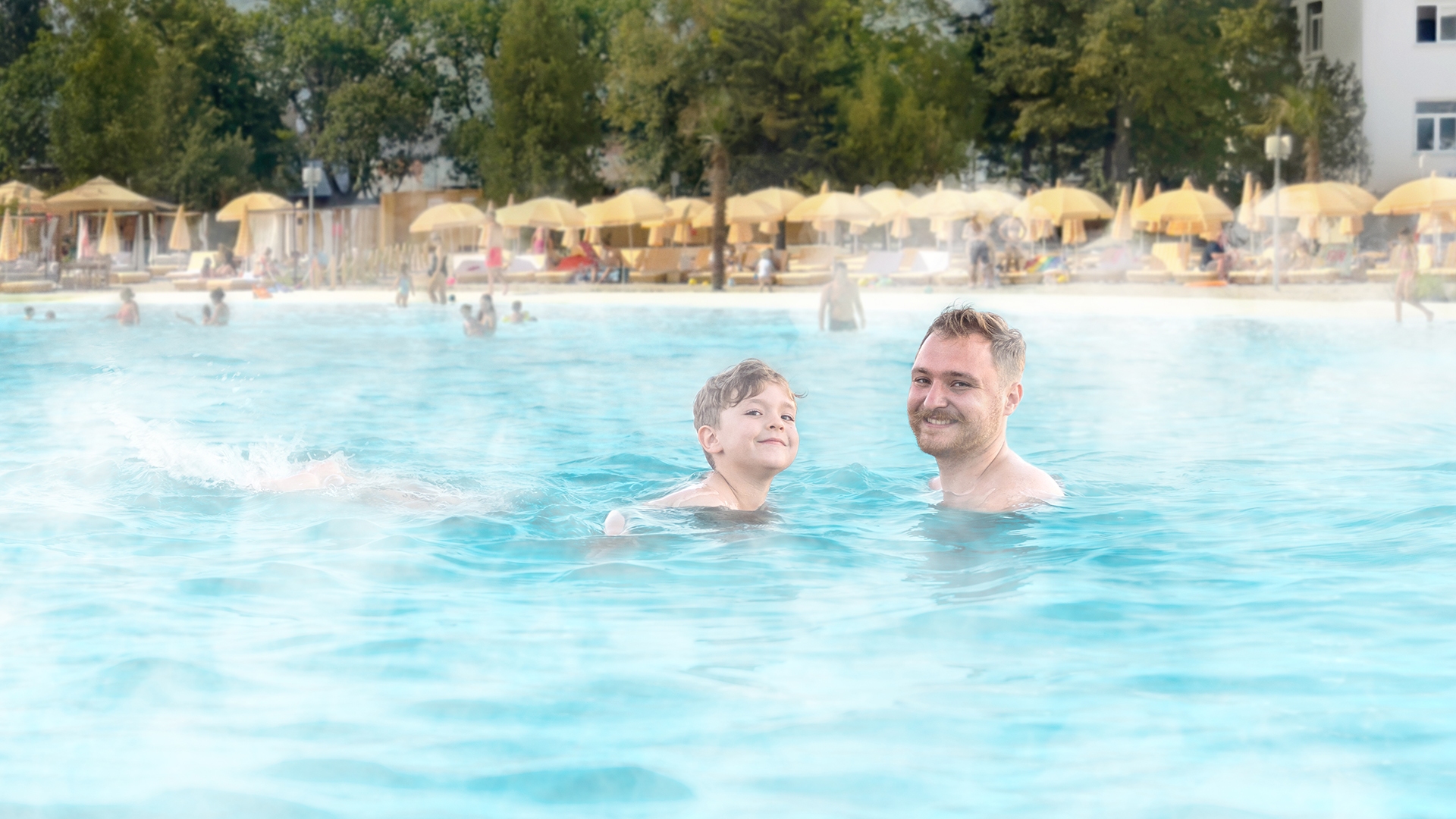 Padre e hijo viviendo la experiencia de playa tropical todo el año en una laguna eco-calefaccionada de Crystal Lagoons